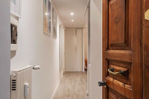 A hallway with a wooden door, a radiator, and a framed picture on the wall.