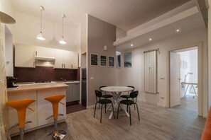 A modern kitchen with a dining area, featuring a round table and bar stools.