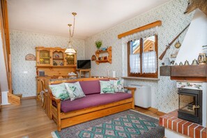 Un salon chaleureux avec un canapé en bois, un tapis à motifs, une cheminée et un téléviseur.