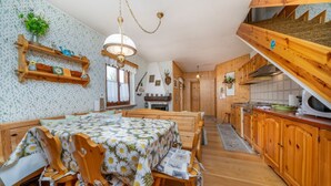 Een gezellige keuken met houten kasten, een eethoek met een tafel en stoelen, en een trap die naar een bovenverdieping leidt.