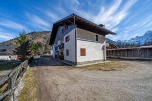 Un bâtiment à deux étages, doté d’un toit en pente, d’une allée gravillonnée et d’une clôture en bois.