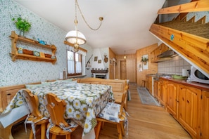 A cozy kitchen with wooden cabinets, a dining area with a table and chairs, and a staircase leading to an upper level.