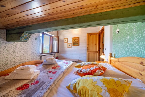 A wooden ceiling, a bed with floral bedding, a window, and a door.