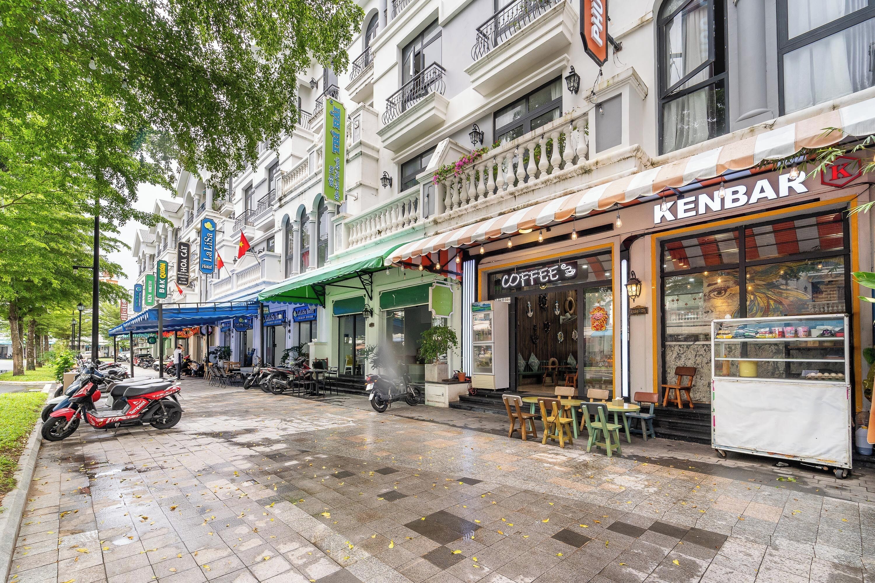 Una calle con una cafetería llamada 'KENBAR' y un edificio con un letrero que dice 'PHOENIX'.