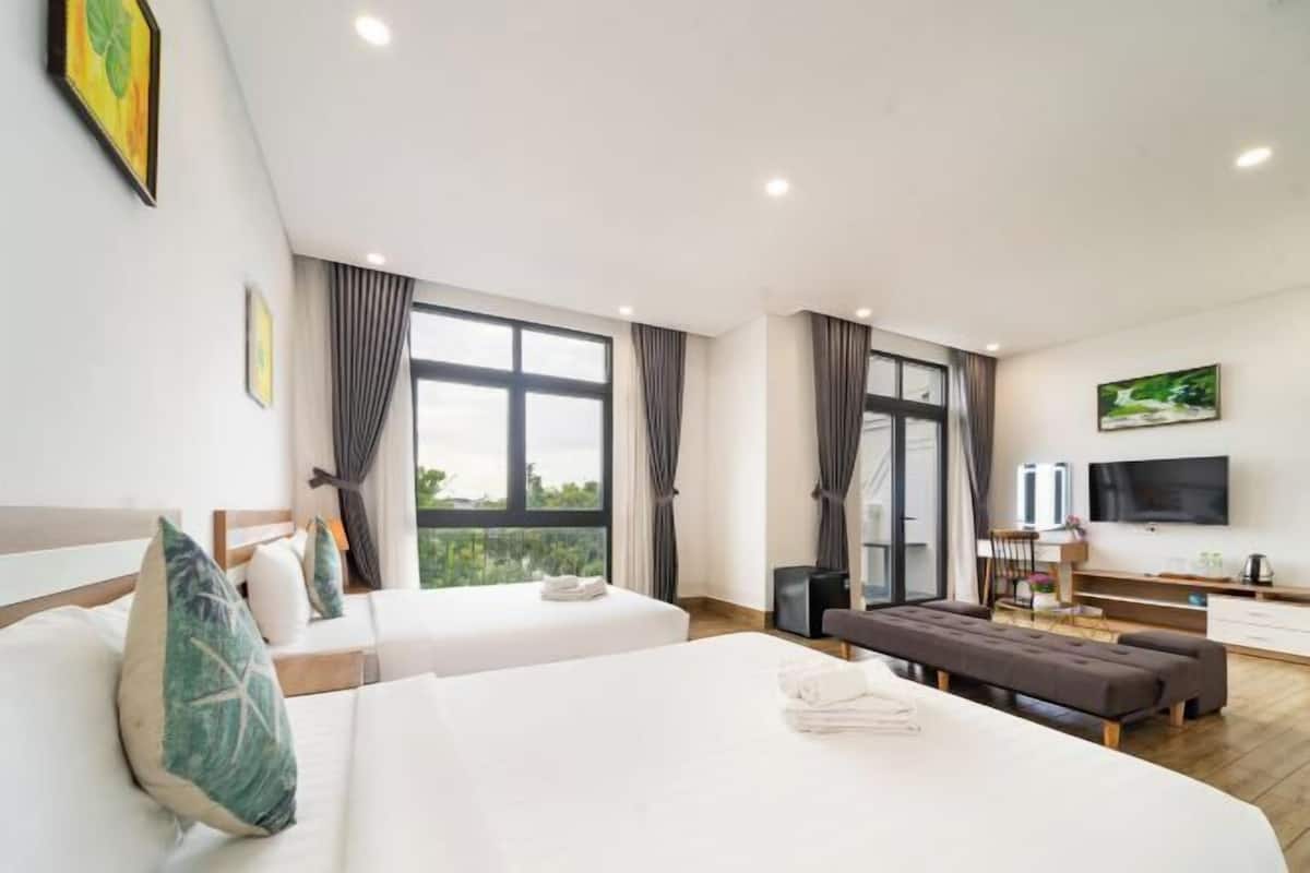 Een hotelkamer met twee bedden, een bureau, een televisie en grote ramen.