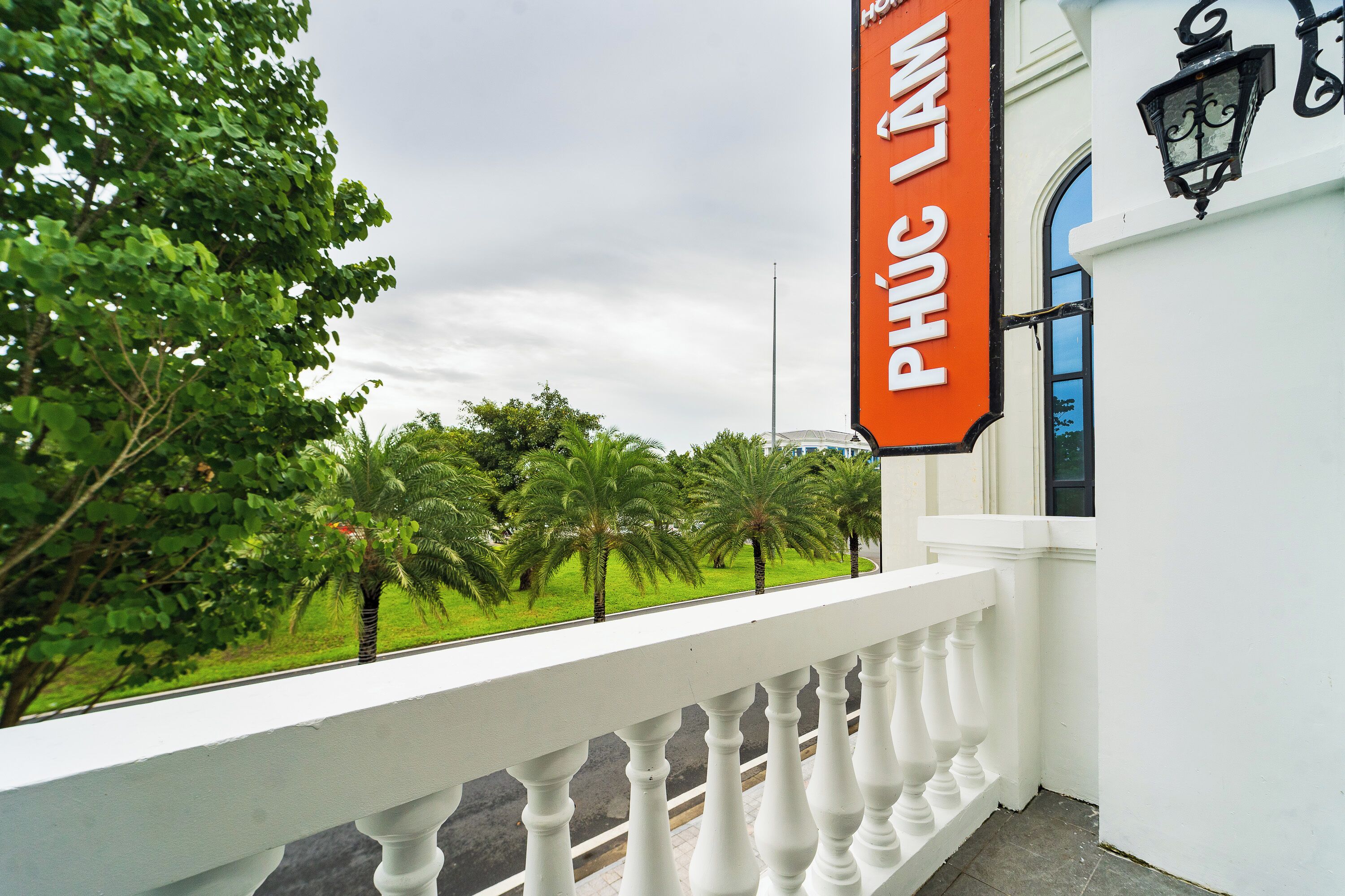Un bâtiment blanc doté d’un balcon avec une balustrade et d’une enseigne sur laquelle on peut lire « PHU CAMA ».