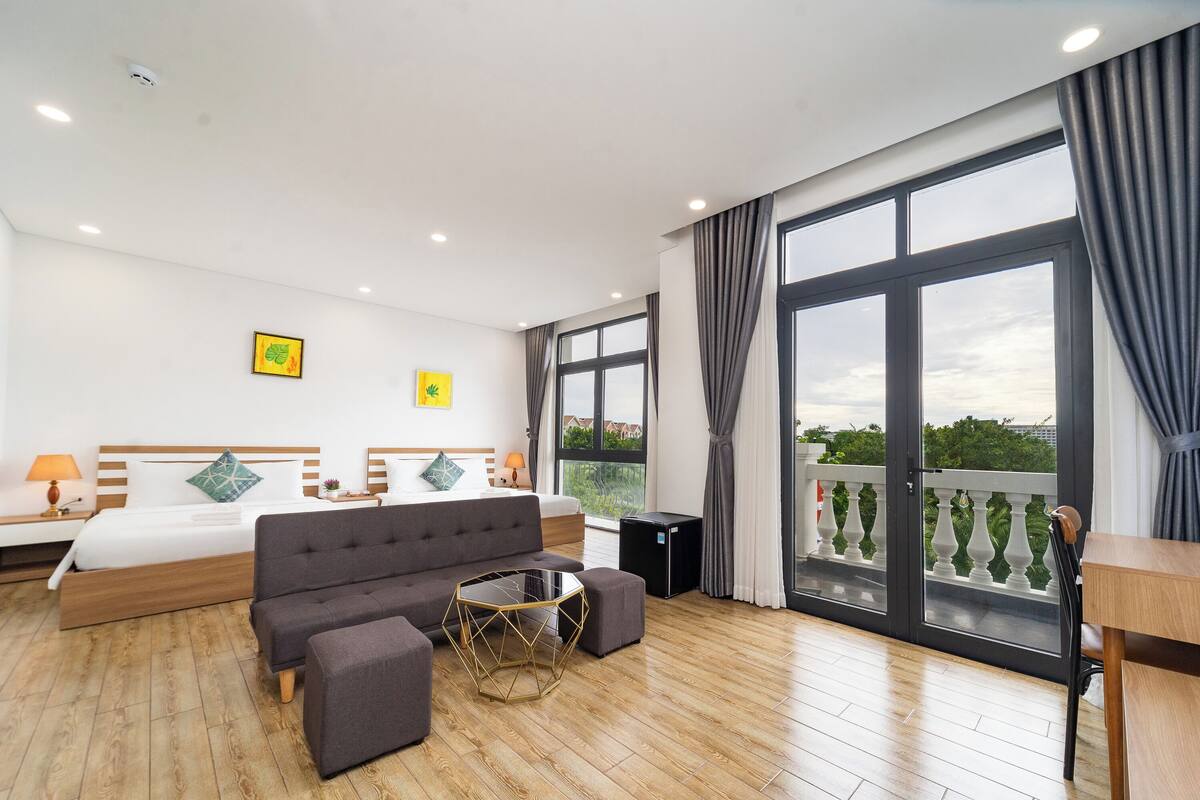 Een moderne hotelkamer met een groot bed, een bank, een klein tafeltje en een balkon met een hekwerk.