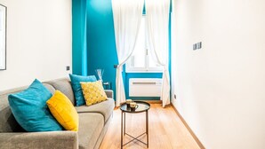 A modern living room with a sofa, a small round table, and a window with curtains. - GuestHost - Old Bridge Lovely Apartment (Firenze)