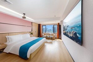 Een hotelkamer met een groot bed, een bank, een bijzettafeltje en een schilderij van een kustlandschap.