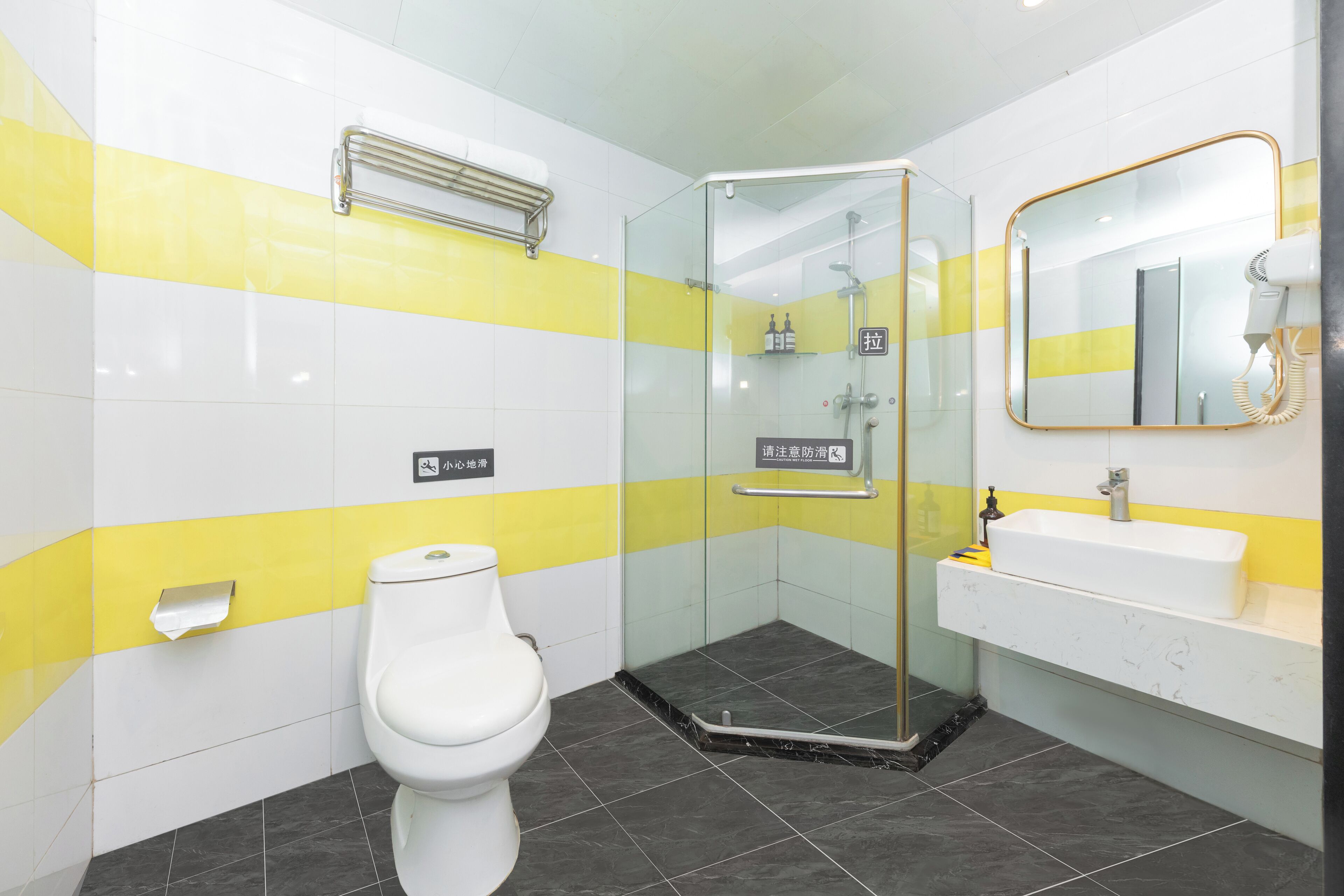 A bathroom with a toilet, a glass-enclosed shower, a sink, and a mirror.