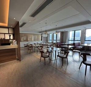 Un hall d’hôtel spacieux, doté de plusieurs espaces salon, d’un comptoir d’accueil et de grandes fenêtres offrant une vue sur la ville.