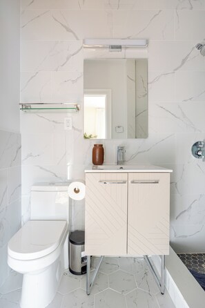 A modern bathroom with a toilet, sink, mirror, and hexagonal tiles. - Prime Luxury with Balcony Wood Fireplace (Yonkers)
