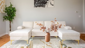 A modern living room with a white sofa set, a glass coffee table, and a potted plant. - Prime Luxury with Balcony Wood Fireplace (Yonkers)