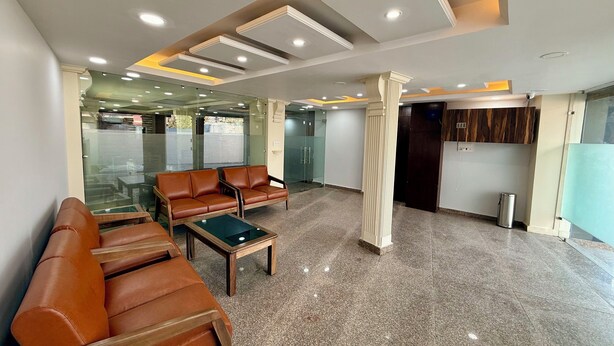 A lobby with leather sofas, a coffee table, and a glass partition. - Hotel Alif Stay (Srinagar)