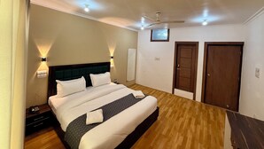 A hotel room with a bed, bedside tables, a ceiling fan, and two doors. - Hotel Alif Stay (Srinagar)