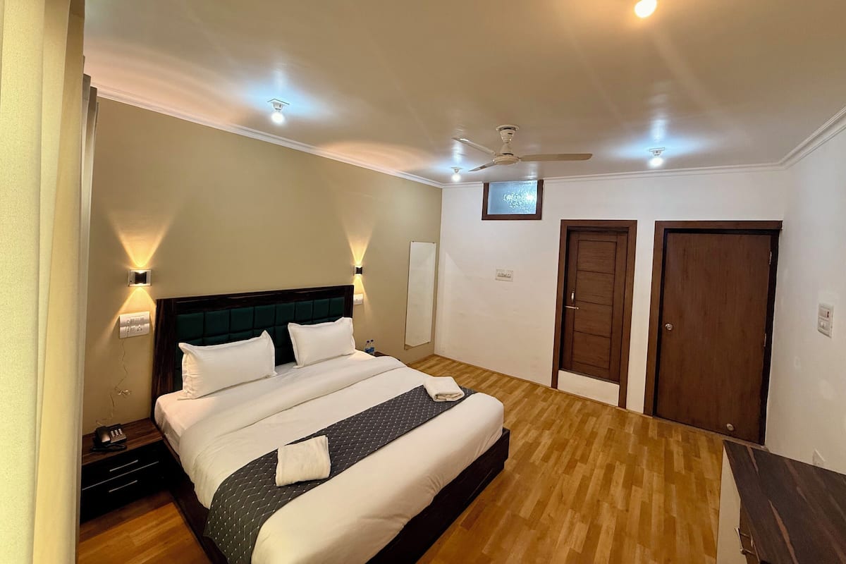 A hotel room with a bed, bedside tables, a ceiling fan, and two doors.