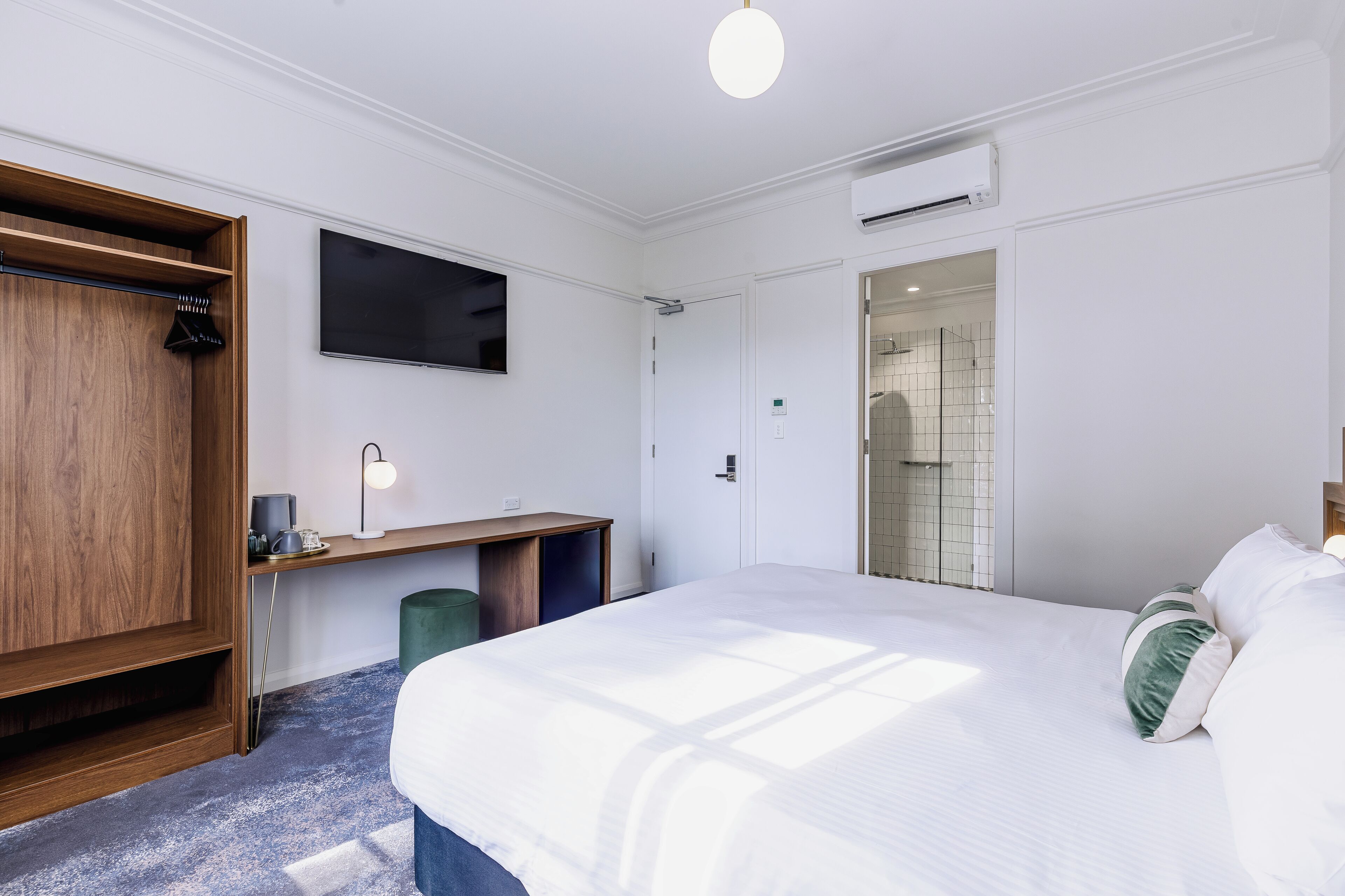 Habitació d'hotel amb un llit, escriptori, televisió i zona de banyera.