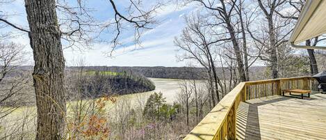 A wooden deck with a bench overlooking a valley.