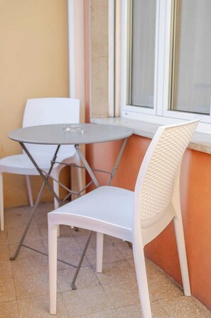 Een klein terras met een ronde tafel en twee witte stoelen.