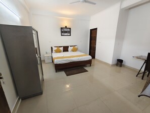 A bedroom with a bed, bedside tables, a trash bin, a ceiling fan, and a wall-mounted light fixture. - hotel Dream Palace  (Noida)