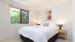 Una camera da letto con un letto grande, due abat-jour, una finestra vista verde e un quadro appeso al muro.