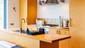 Una cocina moderna con armarios de madera, estufa integrada e iluminación colgante.