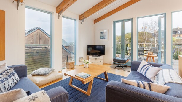 Amplia sala de estar con televisor grande, asientos cómodos y ventanas grandes que ofrecen vistas al exterior.