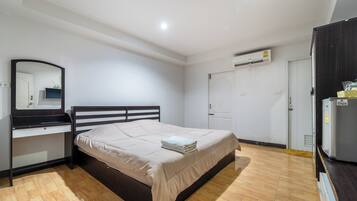 Un dormitorio con cama, escritorio, espejo, armario y equipo de aire acondicionado.