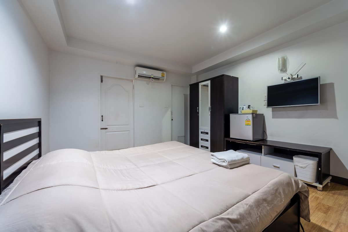 Une chambre à coucher comprenant un lit, une armoire, un téléviseur et un appareil de climatisation.