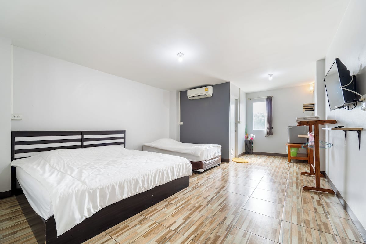 Une chambre d’hôtel avec deux lits, un téléviseur à écran plat fixé au mur et un petit bureau avec une chaise.