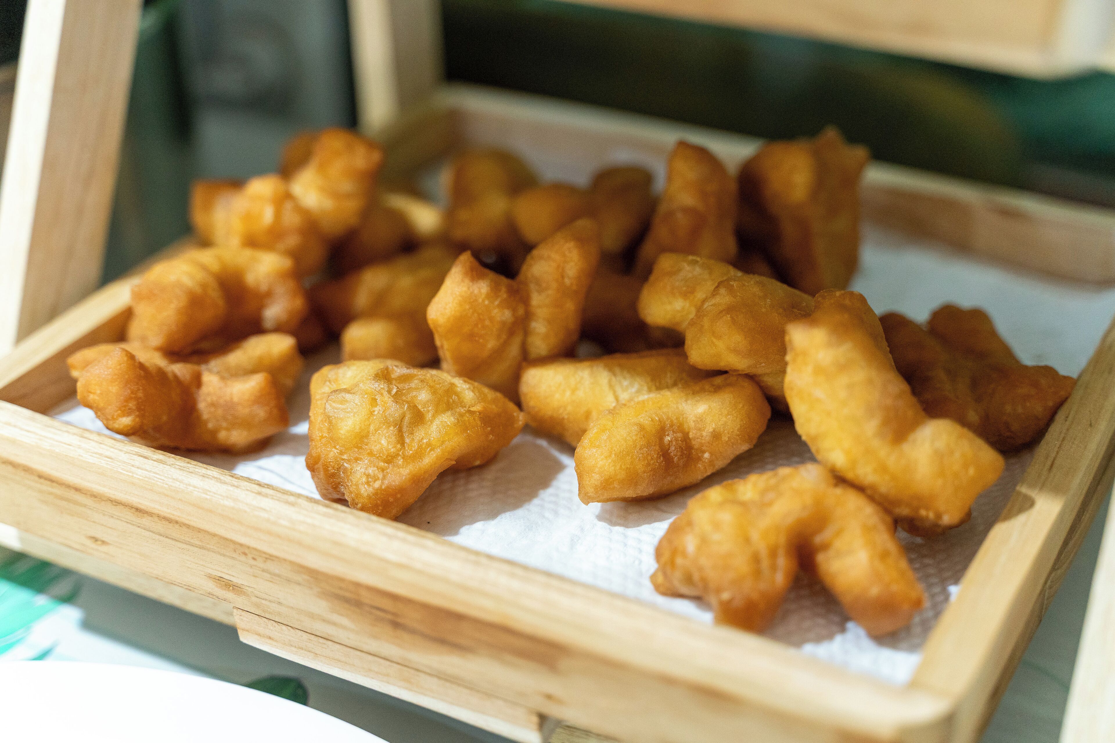 Un plateau en bois rempli de petites douceurs frites, dorées et croustillantes.