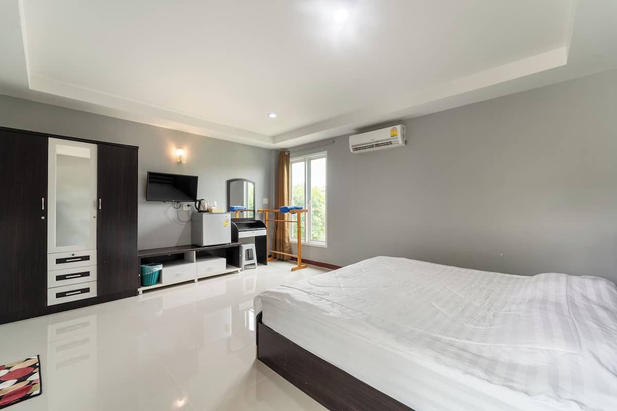 Une chambre moderne avec un grand lit, une armoire, un bureau et un téléviseur.