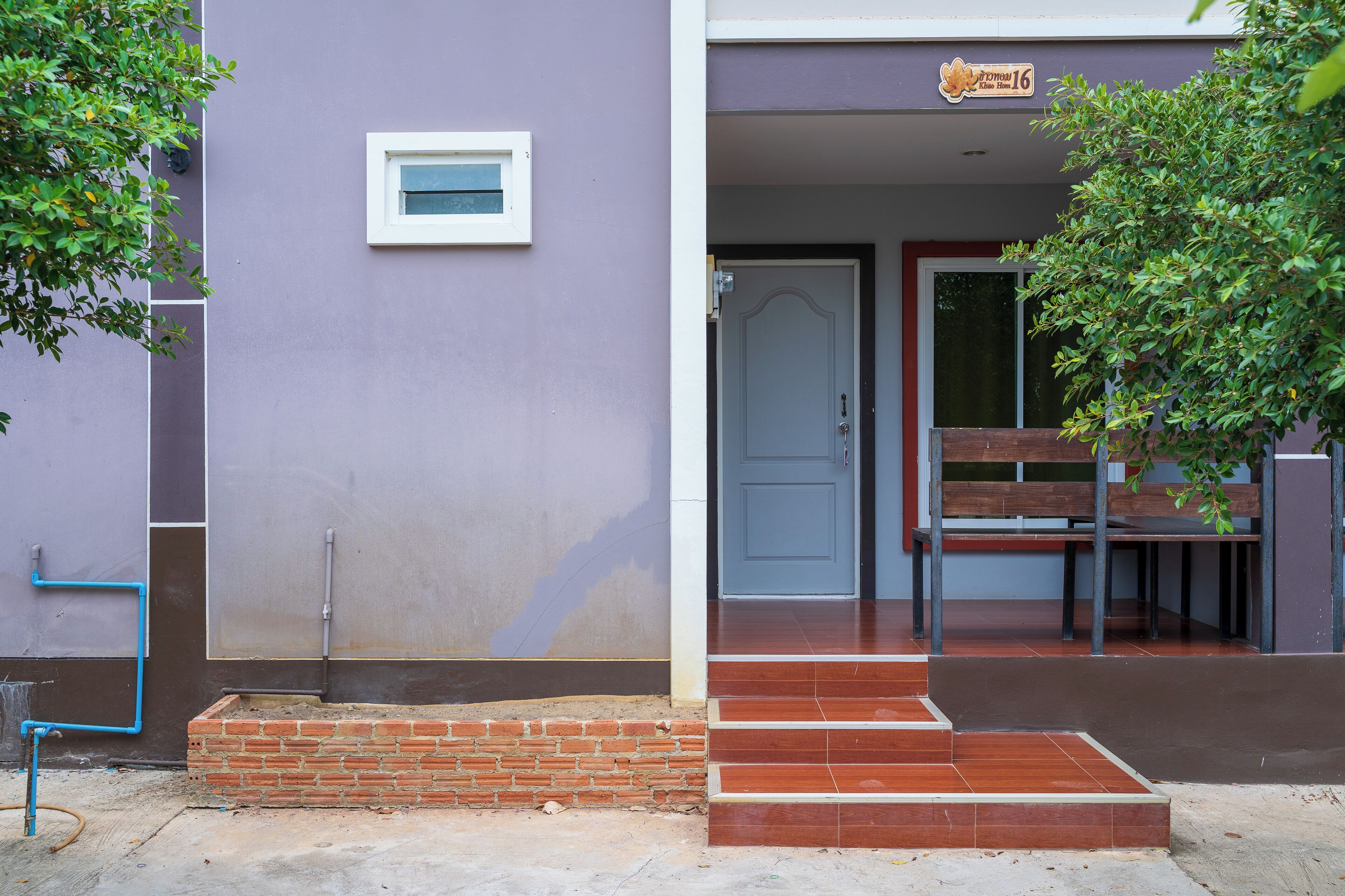 Entrada de un edificio con un escalón de ladrillo, un banco y una puerta.