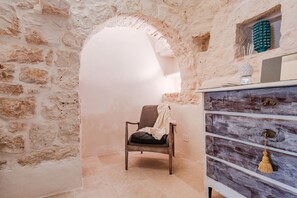 A room with a stone wall, a wooden chair, and a wooden dresser with drawers.