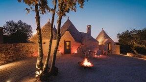 A stone building with conical roofs and a fire pit in the center. - Luxury Apulian Villa inside Trulli with unique pool (Castellana Grotte)