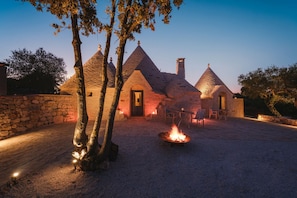 A stone building with conical roofs and a fire pit in the center. - Luxury Apulian Villa inside Trulli with unique pool (Castellana Grotte)