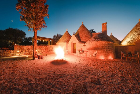 A stone building with conical roofs and a fire pit in the center.