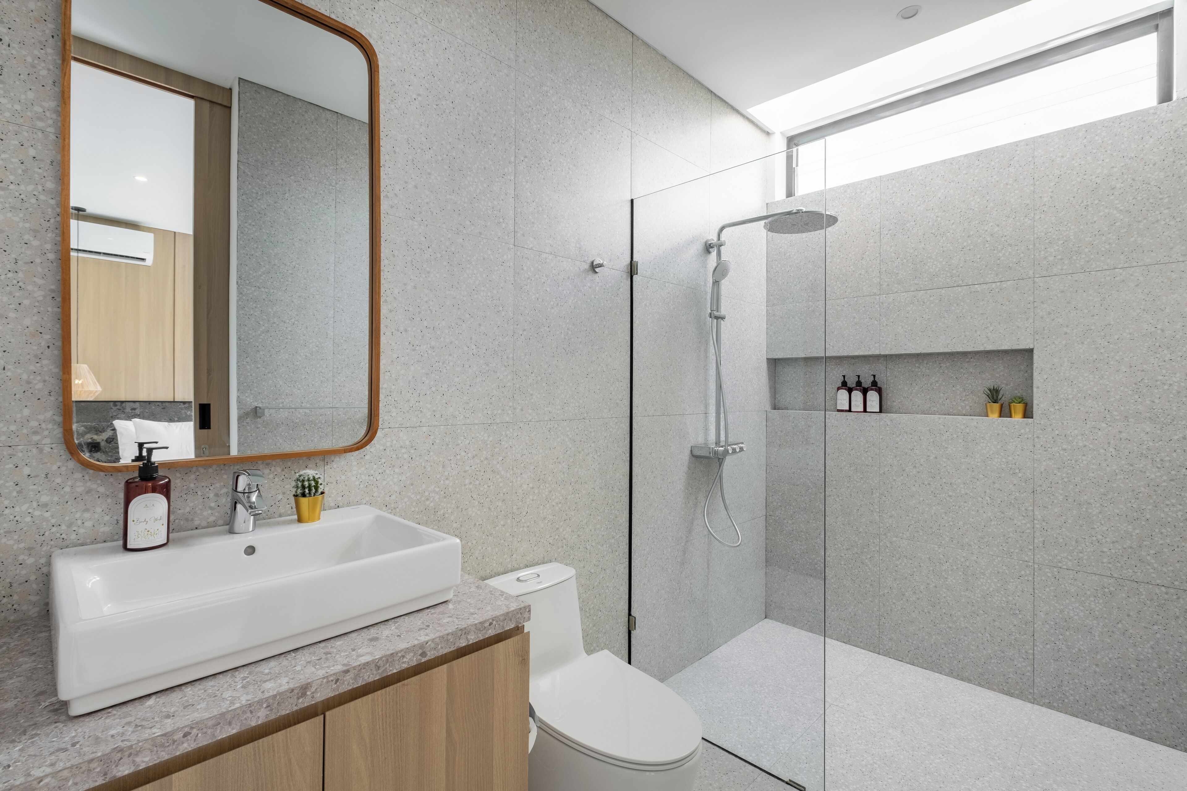 Ein modernes Badezimmer mit großem Spiegel, Waschbecken, Toilette und Duschbereich.