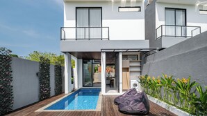 Une maison moderne à deux étages dotée d’une piscine, d’une terrasse en bois et d’un espace salon extérieur.
