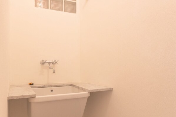 A bathroom with a white bathtub, a small window, and a towel rack.