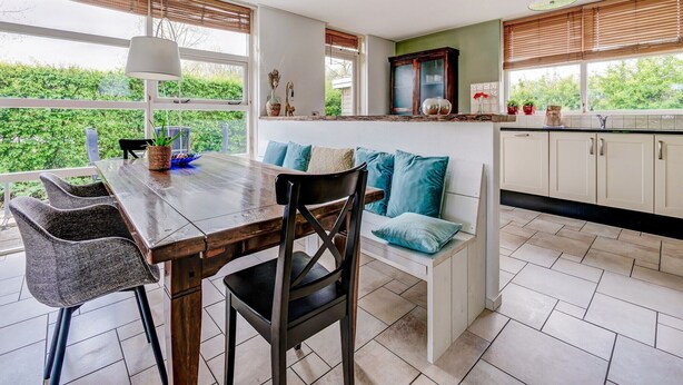 Una cocina moderna con comedor, ventanas amplias y vistas a la vegetación.