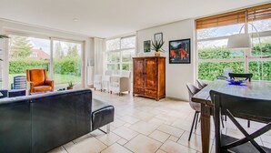 Amplia sala de estar con un gran ventanal, un aparador de madera y una mesa de comedor.