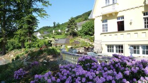 A two-story building with a balcony, surrounded by lush greenery and purple flowers. - Weser Uplands Retreat (Bad Pyrmont-Löwensen)