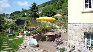 A patio with outdoor furniture, a yellow umbrella, and a stone wall. - Weser Uplands Retreat (Bad Pyrmont-Löwensen)