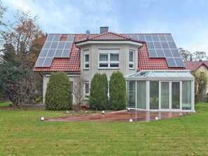 A house with solar panels on the roof, a conservatory, and a well-maintained garden.