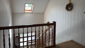 A room with a wooden staircase, a skylight, and a wreath on the wall.