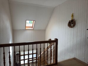 A room with a wooden staircase, a skylight, and a wreath on the wall.