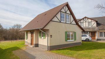 Ein zweistöckiges Haus mit einem geneigten Dach, der Hausnummer '554' an der Fassade und einer gepflasterten Auffahrt, die zum Eingang führt.