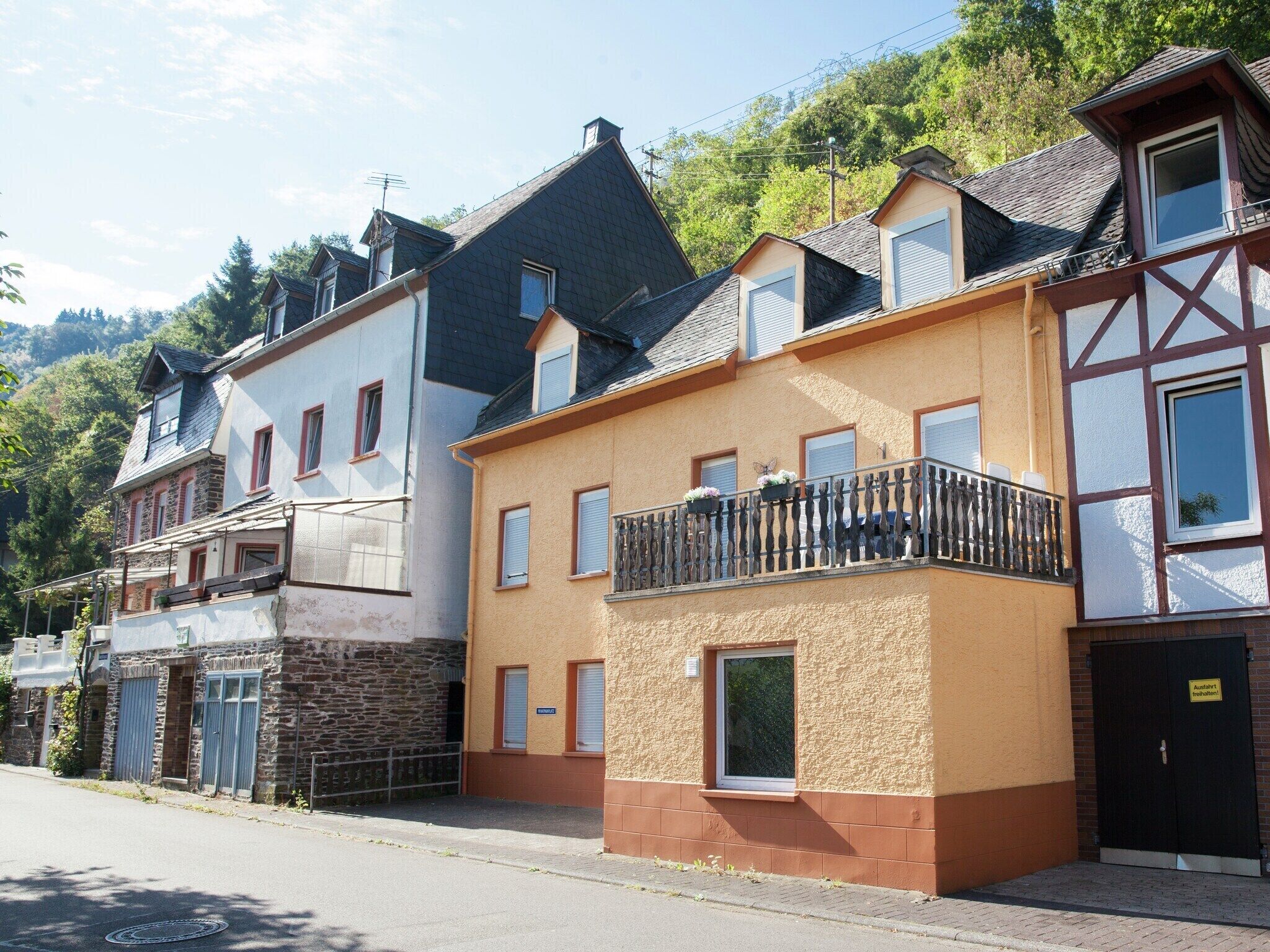 Eine Reihe von Wohnhäusern mit unterschiedlichen Baustilen, darunter ein Haus mit einer Steinaußenwand und ein Fachwerkhäuschen mit Balkon.