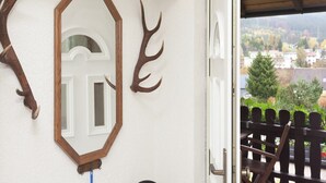 Een kamer met een witte muur, een houten deur en uitzicht op een dorp door een glazen deur.